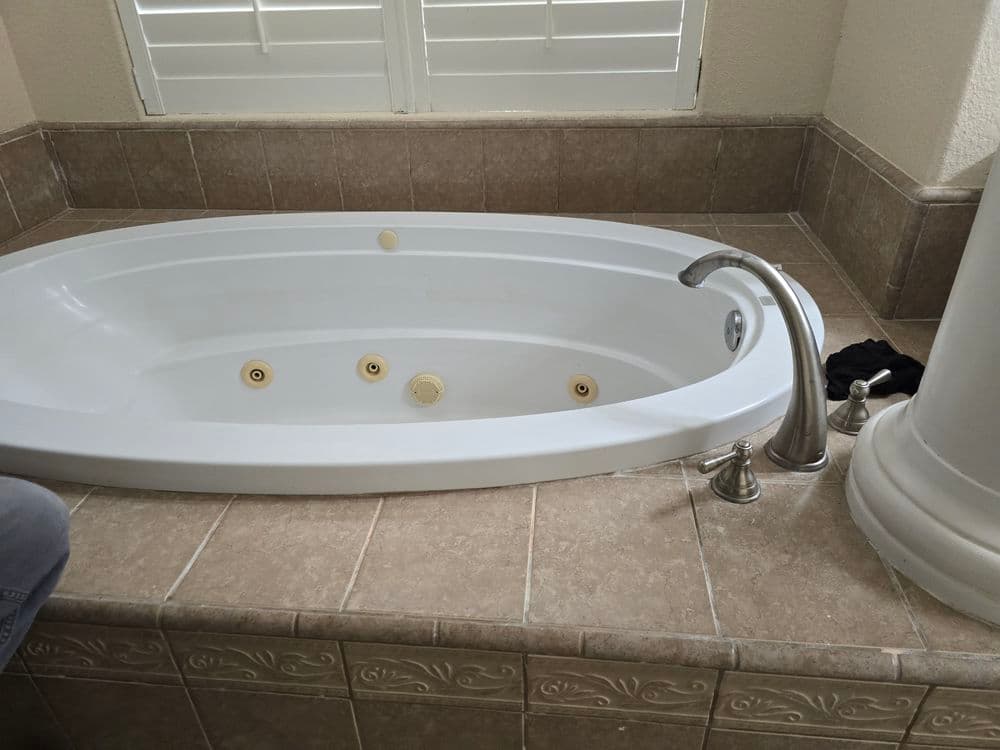 Luxury white bathtub with chrome faucet in a modern bathroom setting.